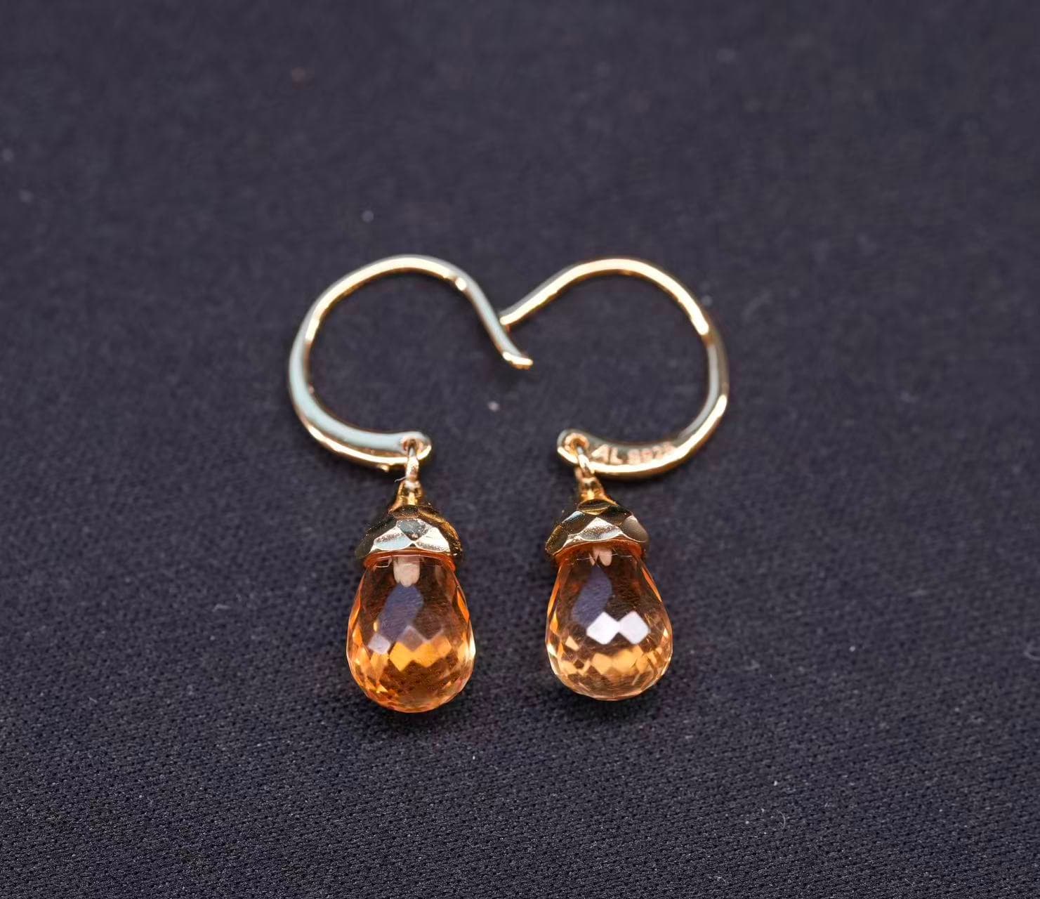 Pair of 18k gold-plated sterling silver drop earrings with faceted honey-gold citrine briolettes on a dark fabric background.